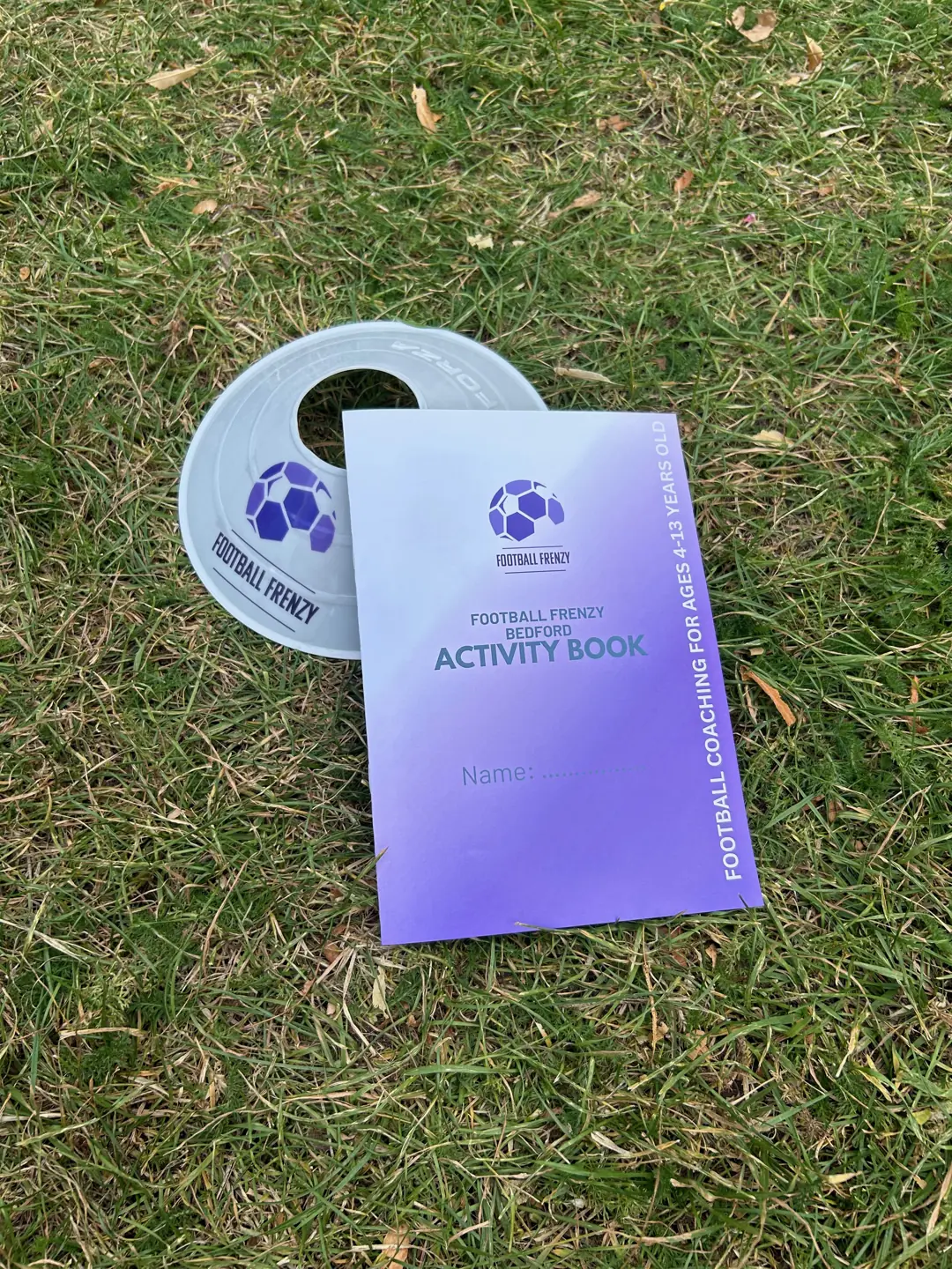 A Football Frenzy activity book and branded hat on grass