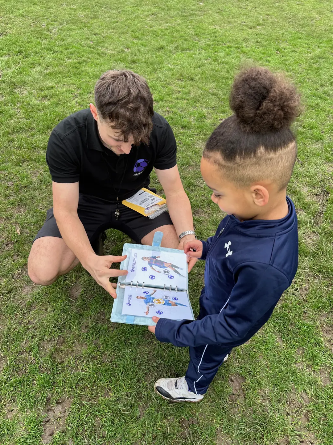 A Football Frenzy coach looking through an activity book with a child