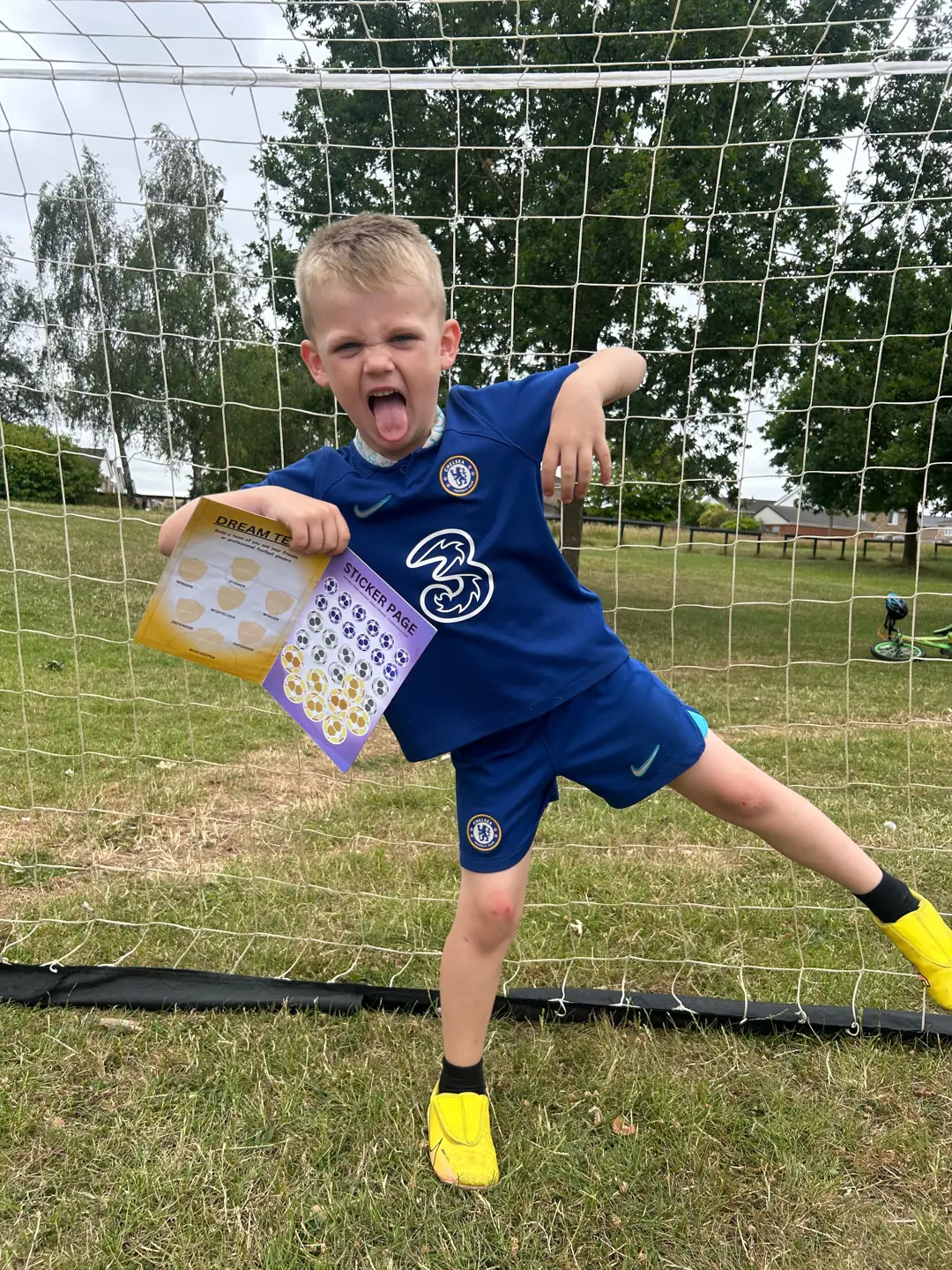 A smiling child jumping beside a goal with a Football Frenzy activity book
