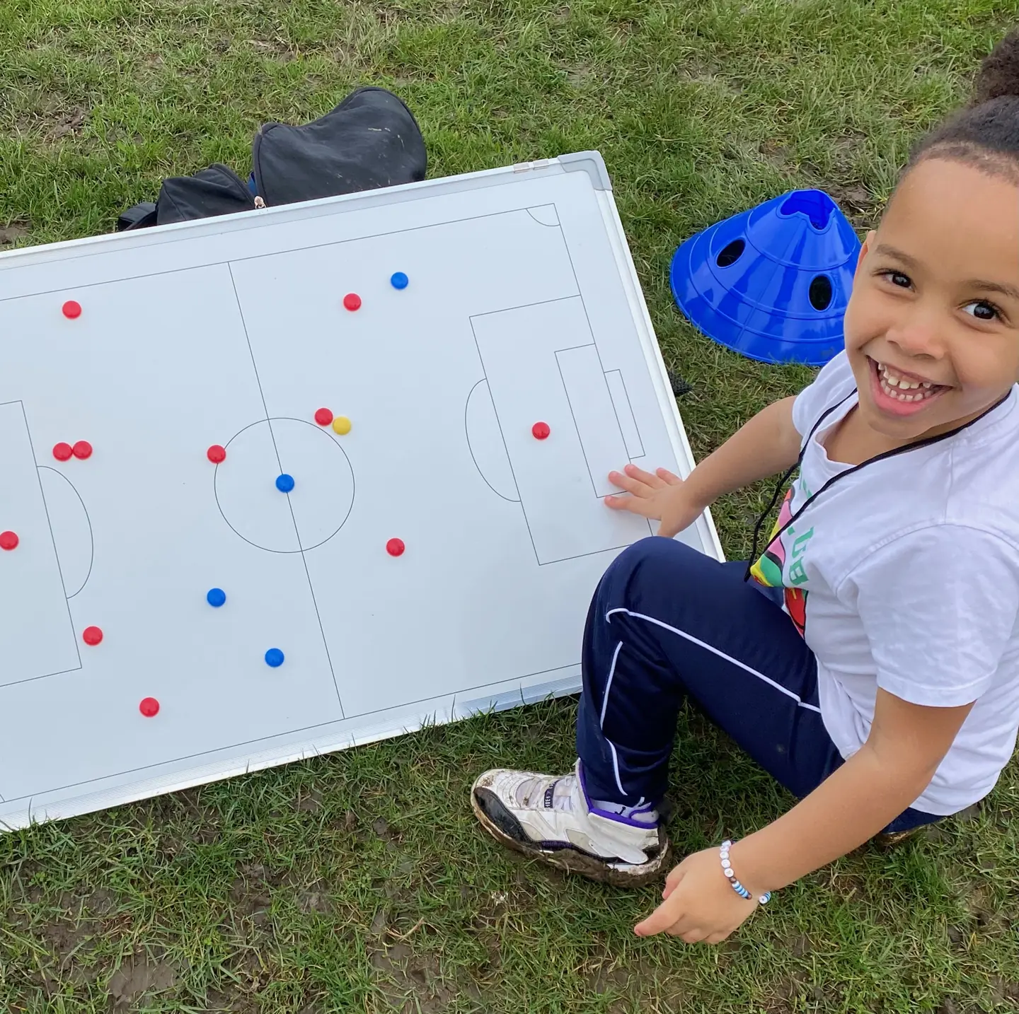 A smiling child beside a Football Frenzy tactics board