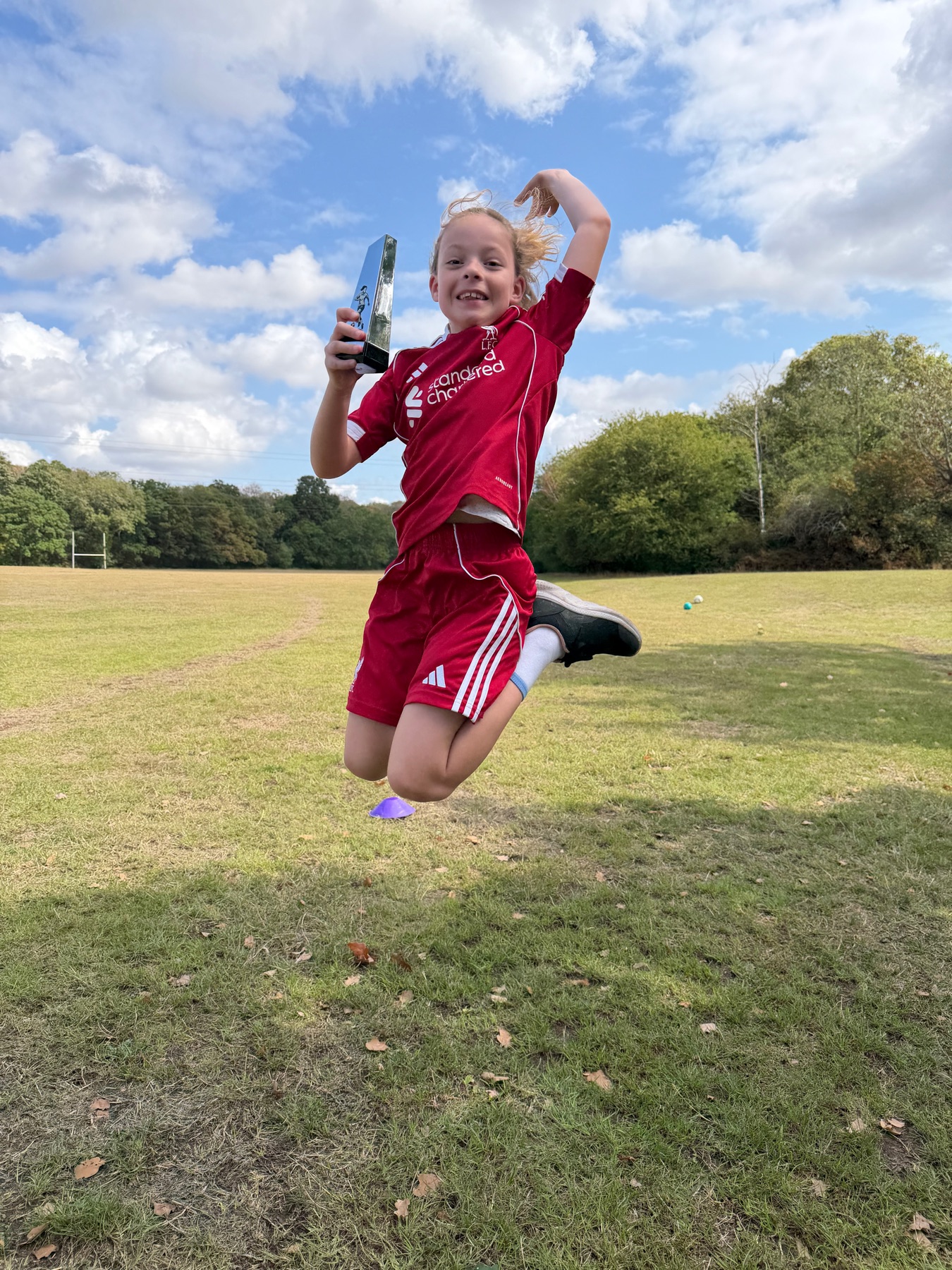 A Football Frenzy child jumping with a trophy at Mowsbury Park