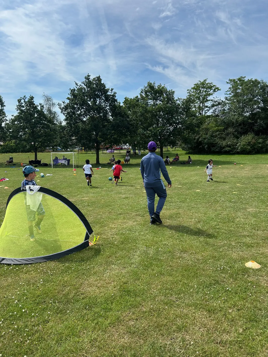 Children playing football with small goals and a coach nearby
